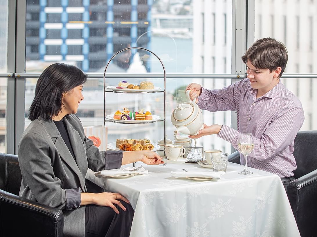 A man pouring tea for his lady at a high tea in James Cook Hotel Grand Chancellor