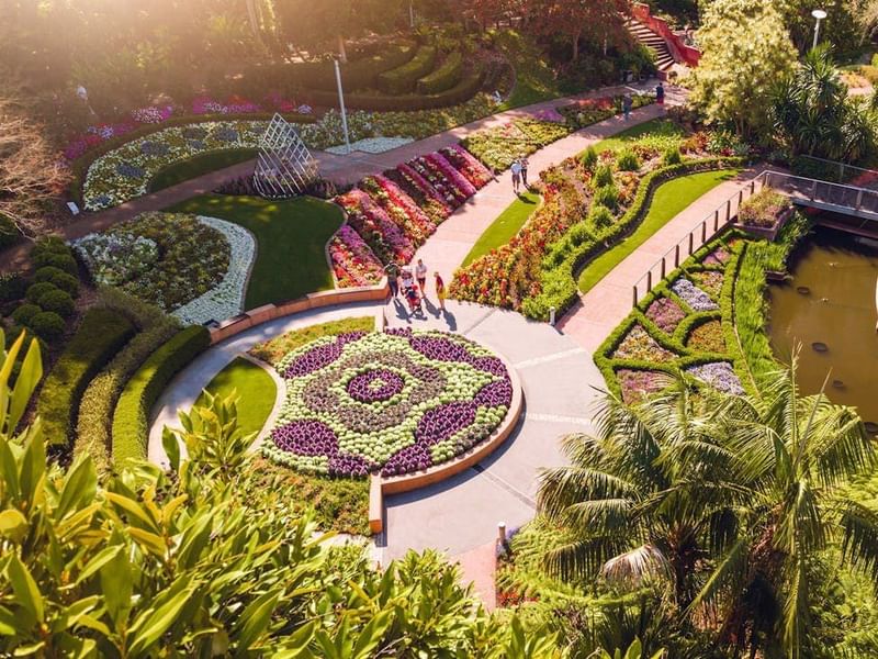 Aerial view of Roma Parkland featuring colorful floral displays, curved pathways, manicured gardens, and a pond.