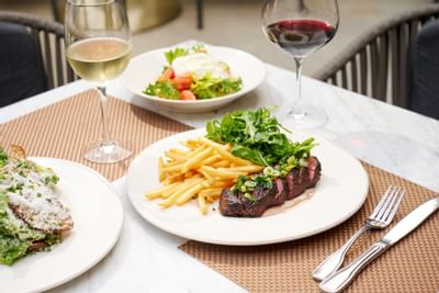 Salad & Steak frites served with wine in restaurant at Luxe Sunset Boulevard Hotel