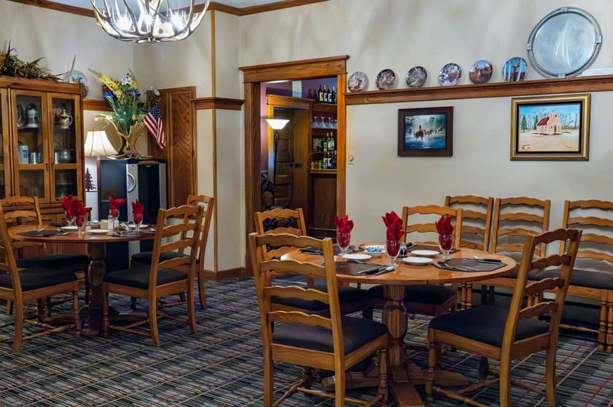 Dining area at The Ranch at Ucross with various table setups, wooden chairs, and decorative wall hangings