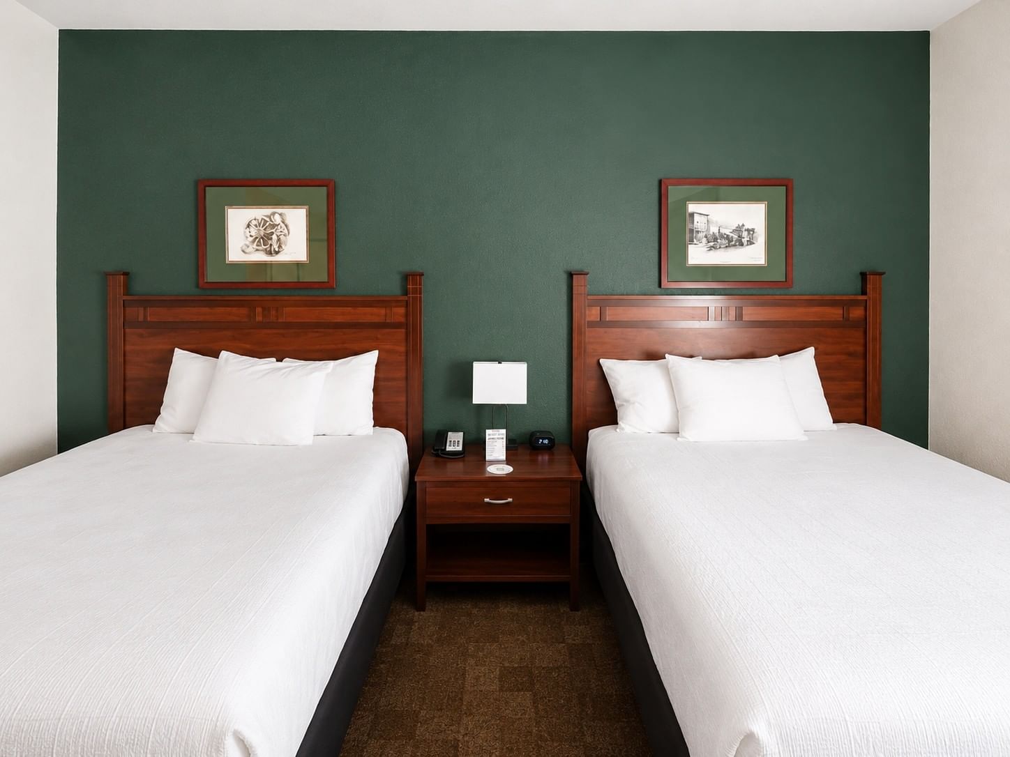Double Queen ADA room with two queen beds, dark wood furniture, and framed artwork at - Boothill Inn