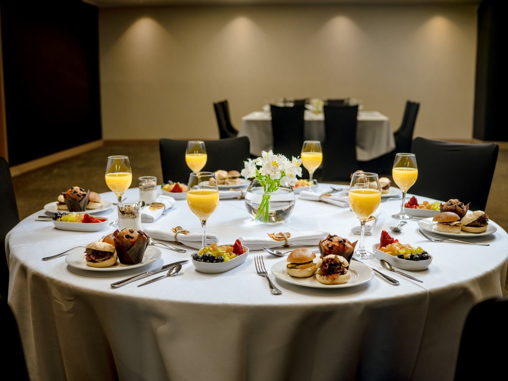Mesa de desayuno con fruta, pan y vasos de zumo de naranja en el hotel HCC Costanera Concepción.