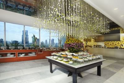 Bazaar buffet table with white bowls under a beaded chandelier, beside a flower arrangement near Megapolis Hotel Panama