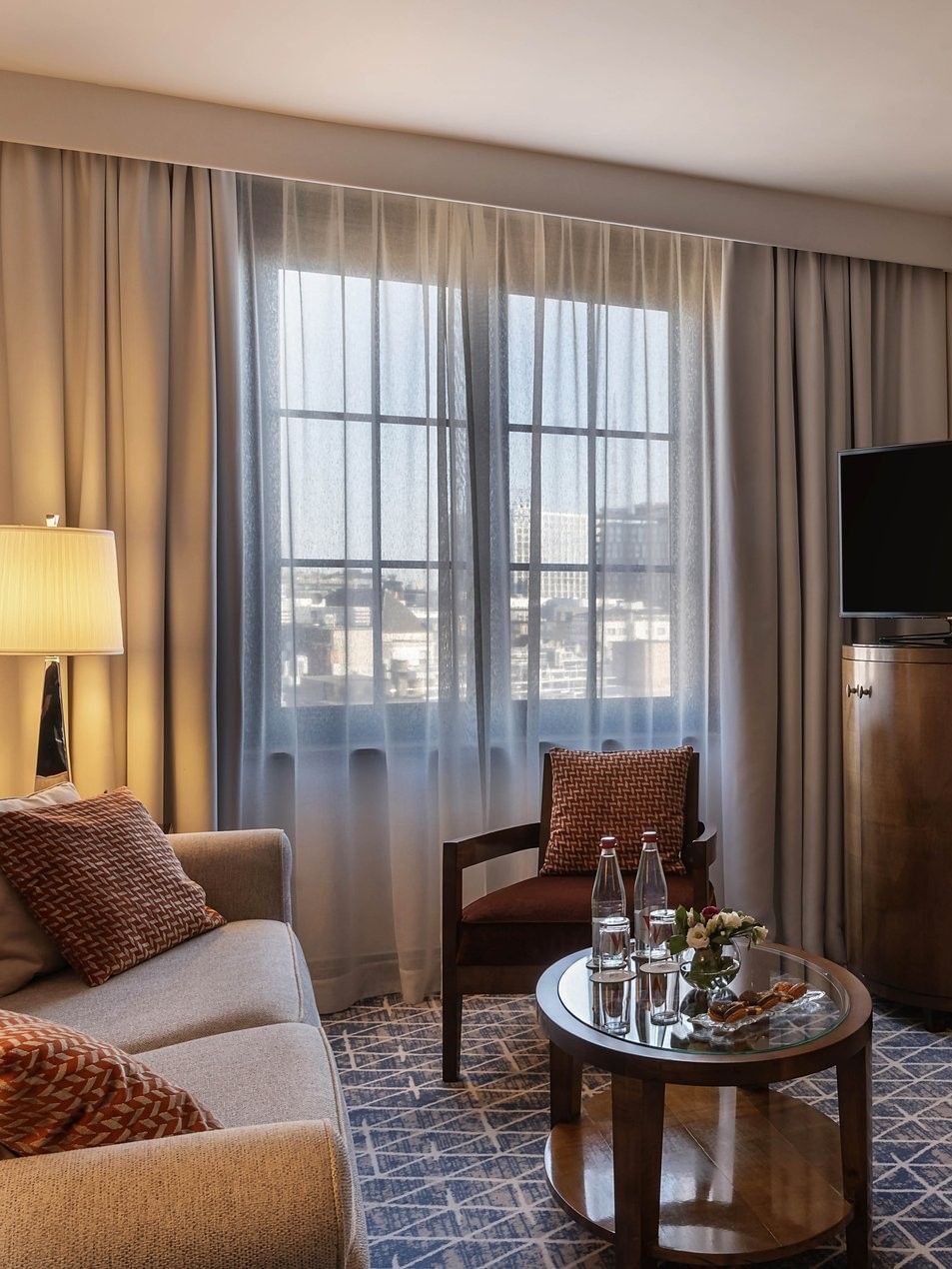 Warwick Suite TV lounge featuring a sofa near the bed with an ottoman at Warwick Grand Place Brussels