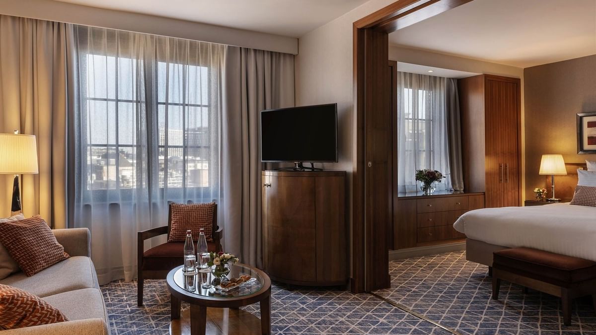 Warwick Suite TV lounge featuring a sofa near the bed with an ottoman at Warwick Grand Place Brussels