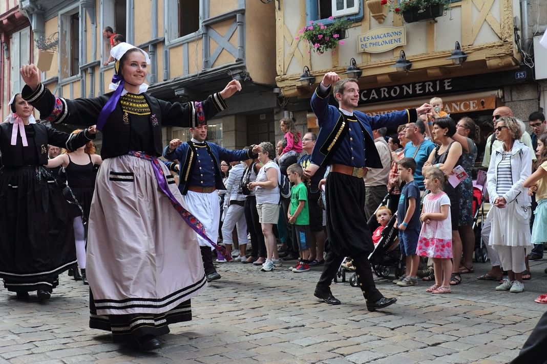 Scène de rue vibrante avec des gens en costumes traditionnels près des Hôtels Oceania