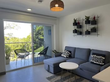 Living area with comfy couch and balcony in an apartment at Punta Leona Beach Club & Nature Resort