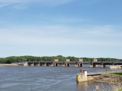 Panoramic view of the river with Lock & Dam 12, featuring multiple gates under a blue sky near Off Shore Resort