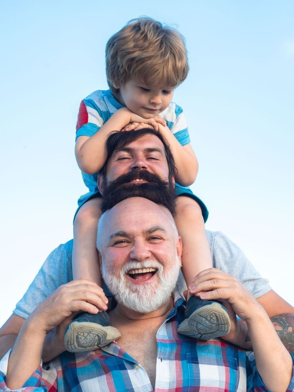 Young boy sitting on the shoulders of a man with a gray beard, positioned by an open sky at Warwick Hotels & Resorts