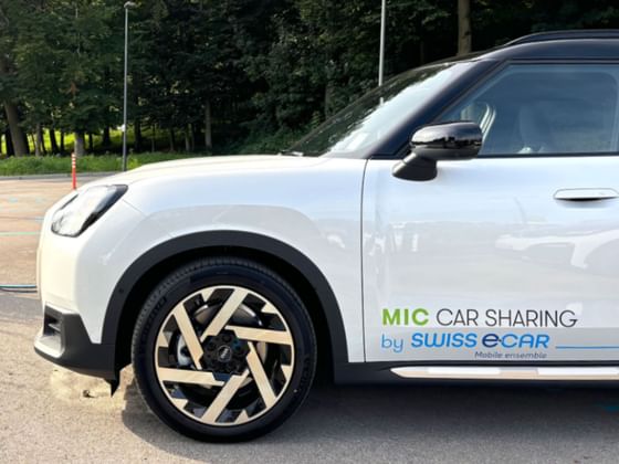 Parked white car with MIC Car Sharing signage at Hotel des Innovations
