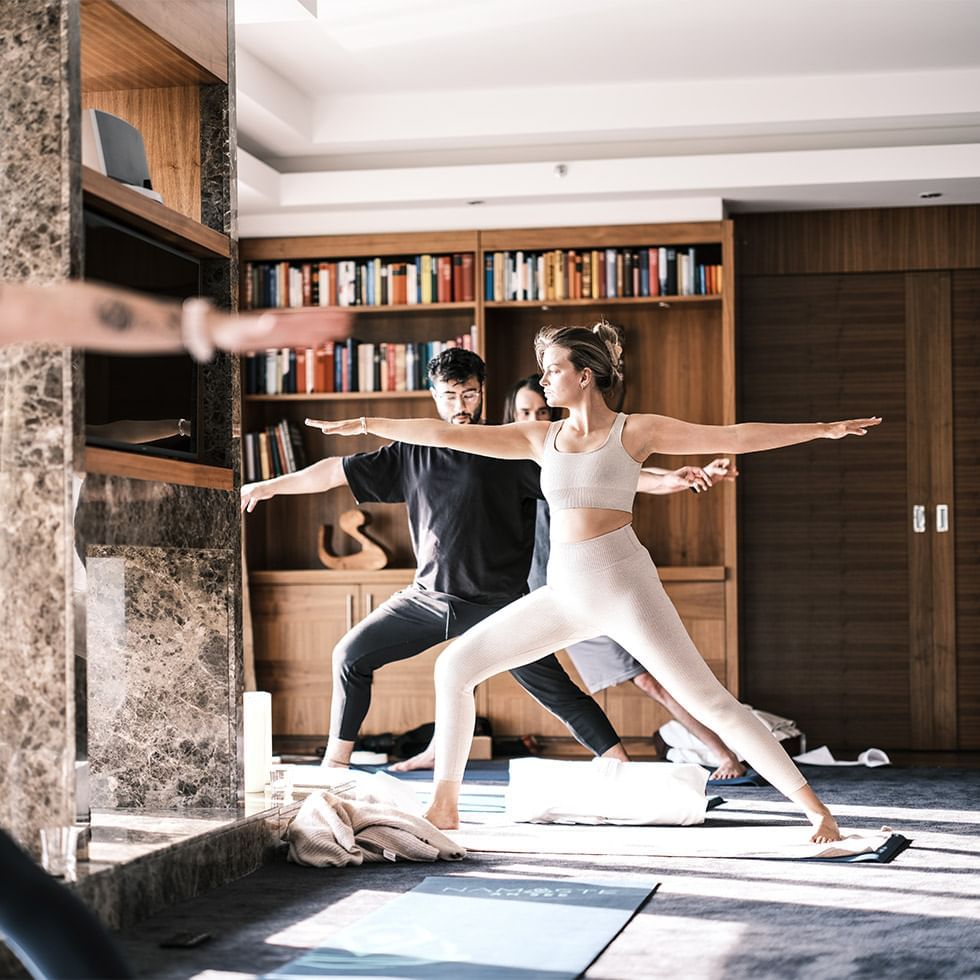 People doing yoga together in a room with bookshelves at Falkensteiner Schlosshotel Velden