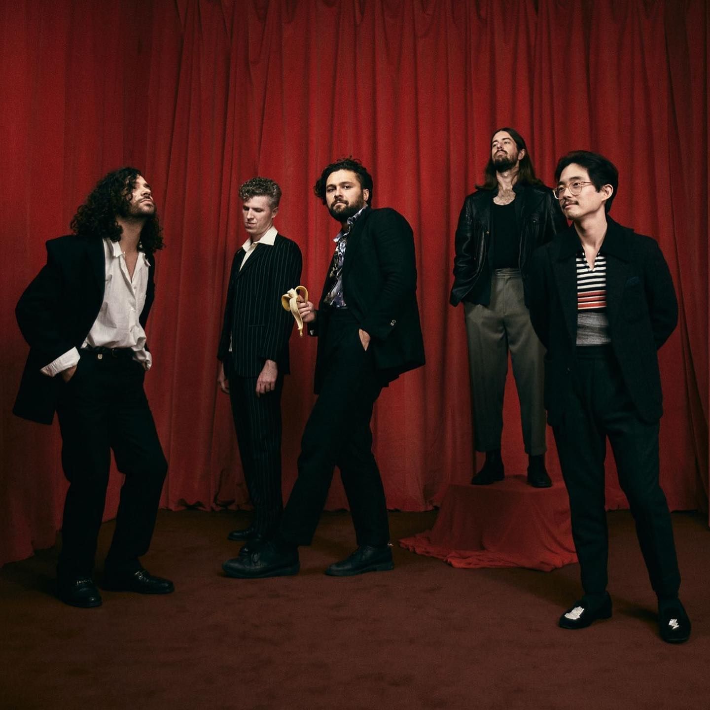 5 men standing in front of a red curtain