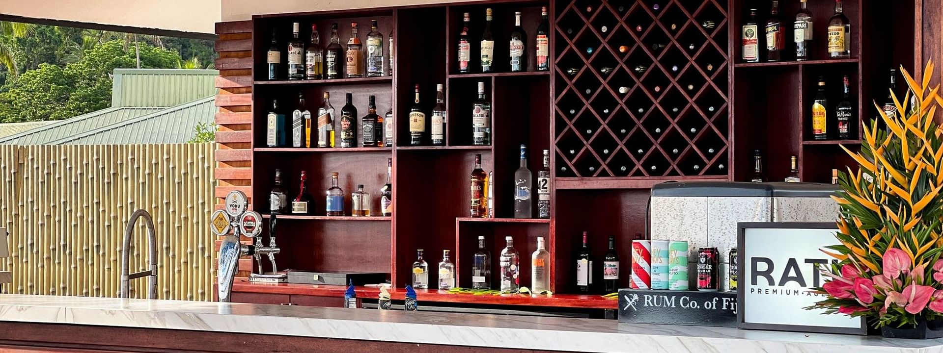 Shelves stocked with liquor bottles behind a bar counter at Sunset Bar in Korolevu at The Naviti Resort Fiji