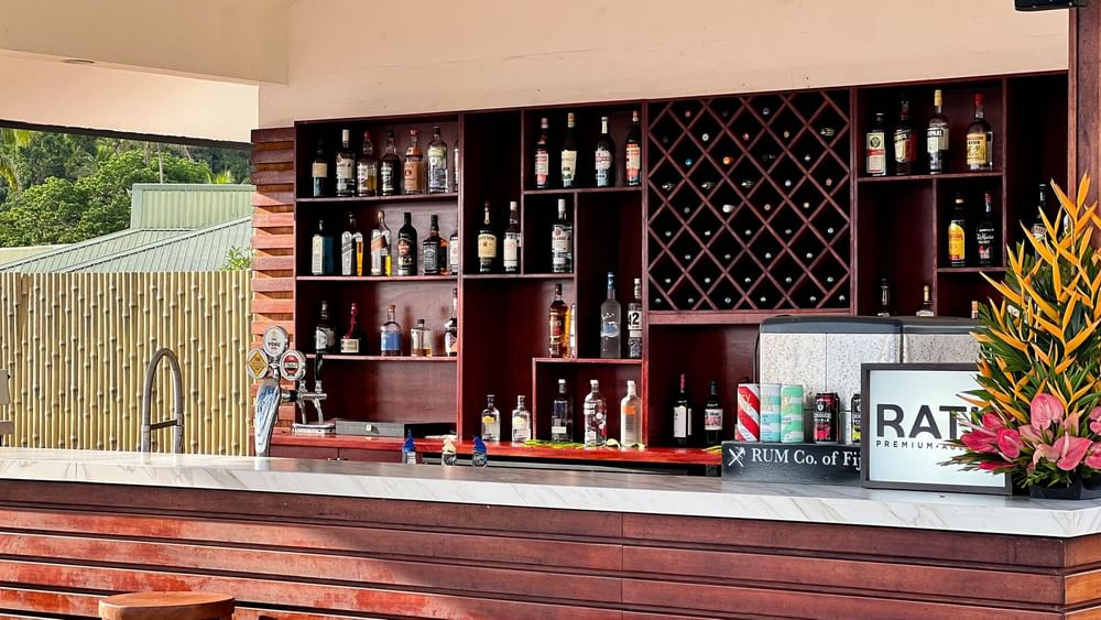 Shelves stocked with liquor bottles behind a bar counter at Sunset Bar in Korolevu at The Naviti Resort Fiji.