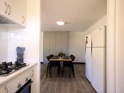 Modern kitchen with gas stove, refrigerator, and dining area at UniLodge at Curtin University - Vickery House.