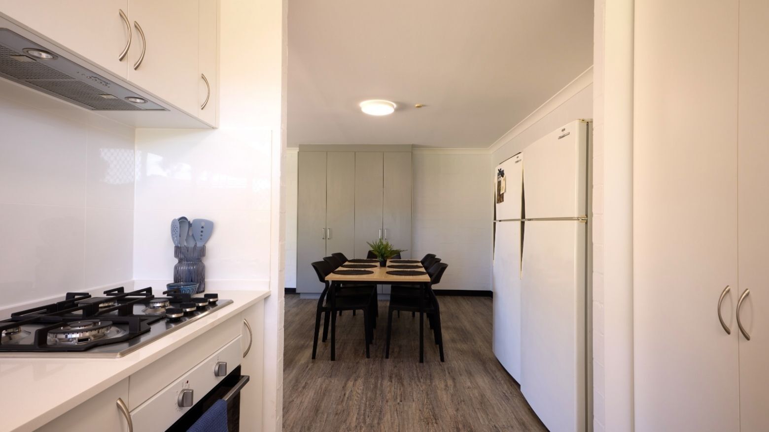 Modern kitchen with gas stove, refrigerator, and dining area at UniLodge at Curtin University - Vickery House.