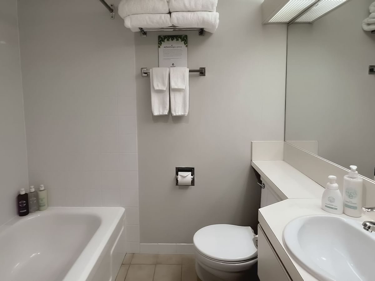 Bathroom with towels, toilet, mirror, bath and sink