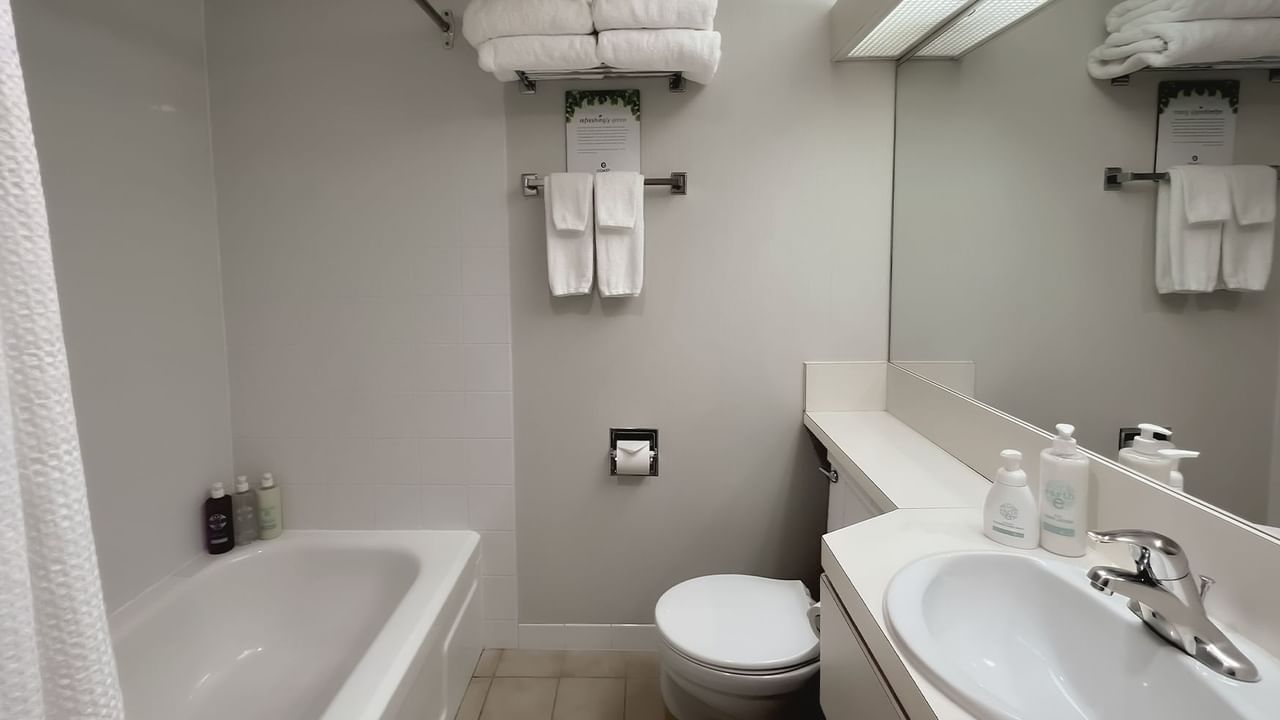 Bathroom with towels, toilet, mirror, bath and sink