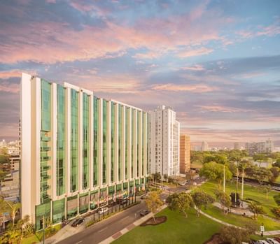 Exterior view of Hotel Los Delfines & Casino with motor lobby, surrounded by greenery and cityscape