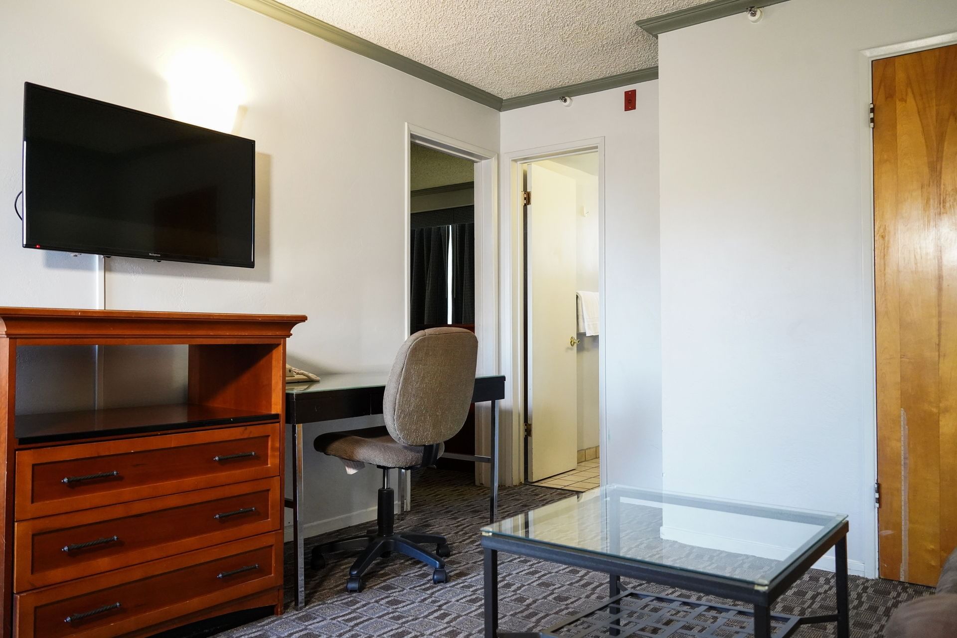 A hotel room with a TV, desk, and coffee table.