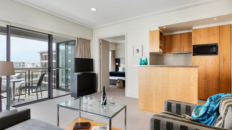 Open-plan living area with a kitchenette by the window in Marina Deluxe One Bedroom Suite at Sebel Auckland Viaduct Harbour