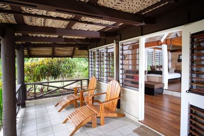 Beachfront Bures with wooden chairs overlooking a lush garden at Musket Cove Island Resort & Marina