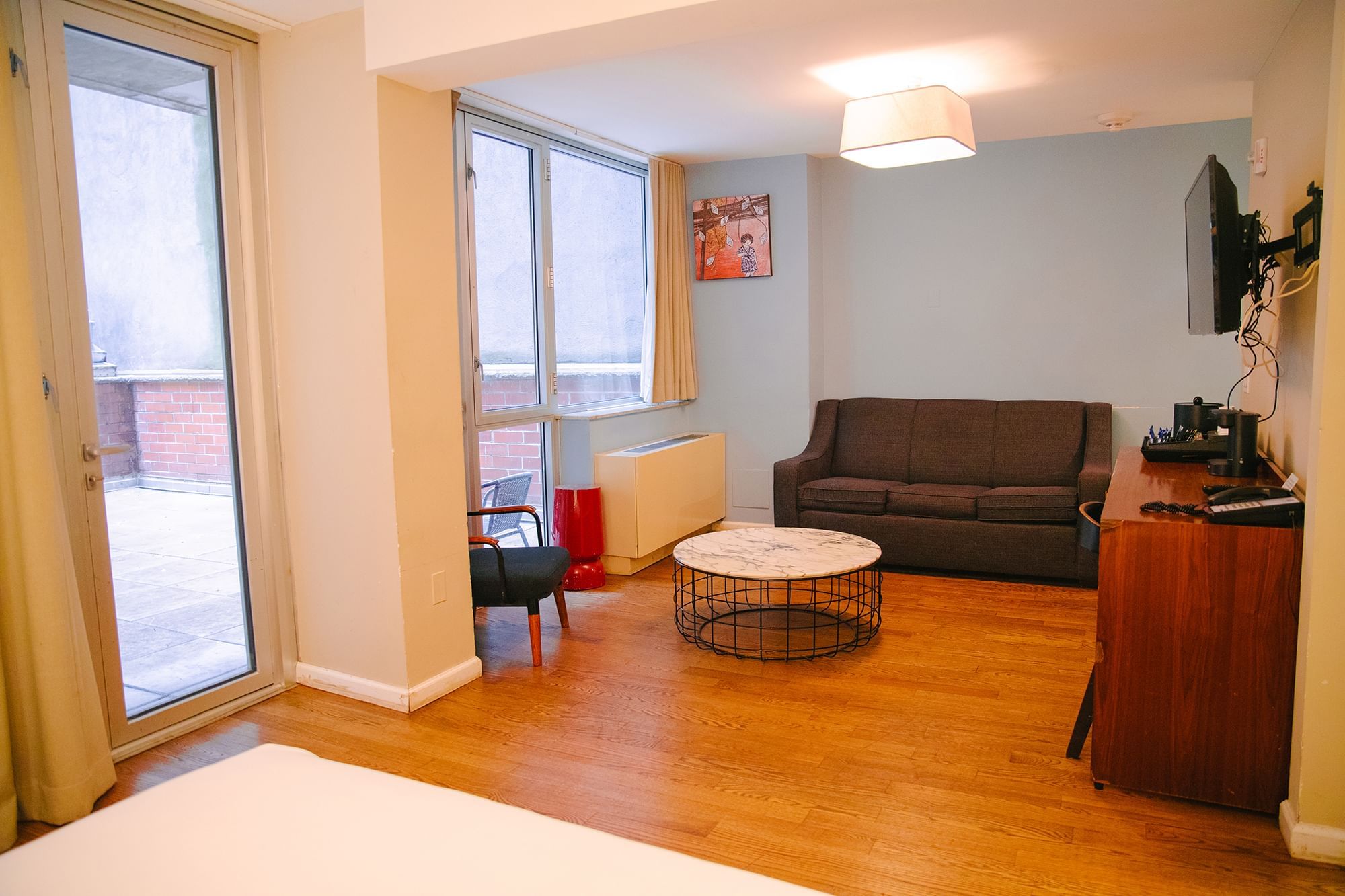 A wide view of a hotel room with a sofa, coffee table, TV, and window.