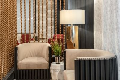 Lounge with bucket chairs by the gold lamp, and decorative rope partitions at The Riverwalk Plaza Hotel