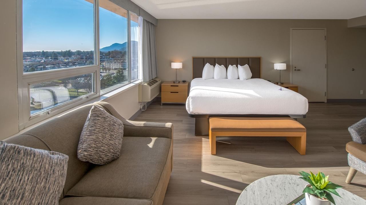 Hotel room with a large bed, couch, and scenic view.