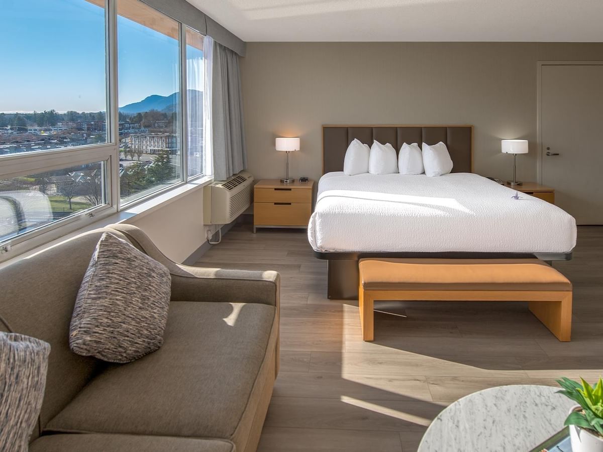 Spacious room with large bed, sofa, and a large window with views.