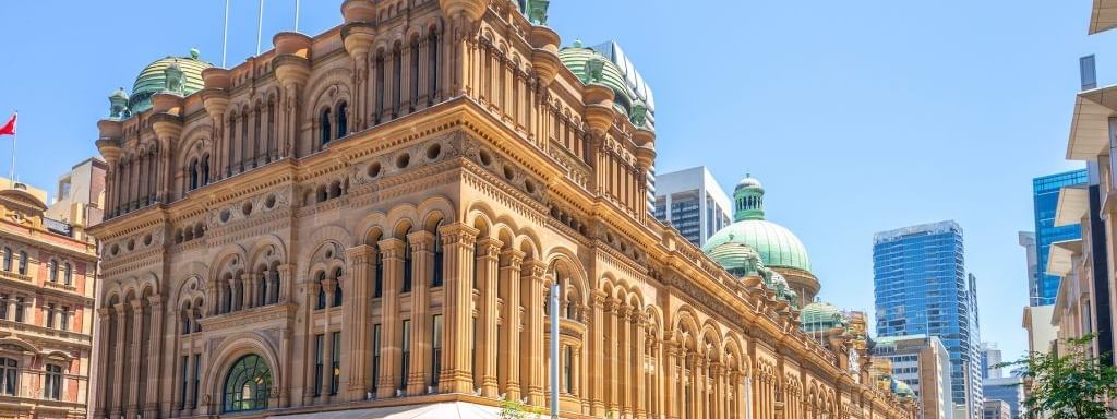The historic Queen Victoria exterior with people and trams ear Novotel Sydney on Darling Harbour