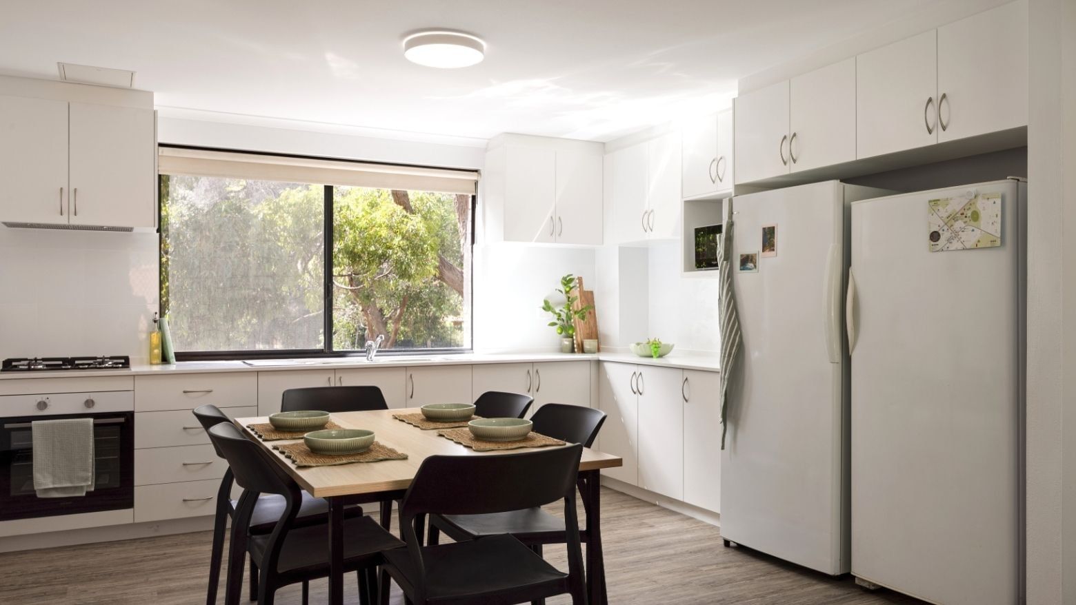Dining area with table and chairs, large window, and modern kitchen at UniLodge at Curtin University - Erica Underwood House.
