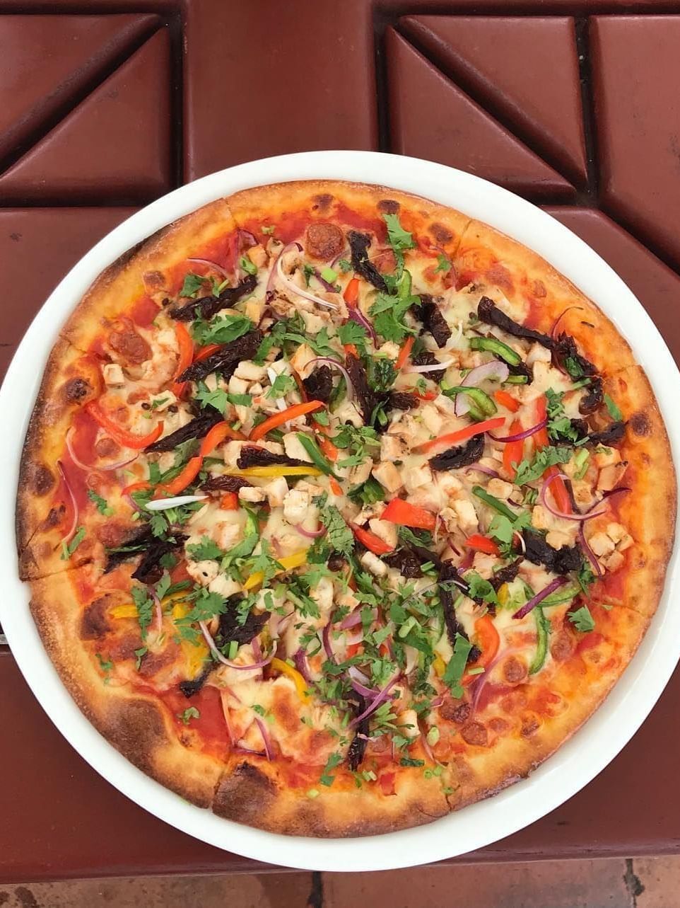 Plate of gourmet pizza on wooden table at Serena Beach Resort & Spa in Mombasa.