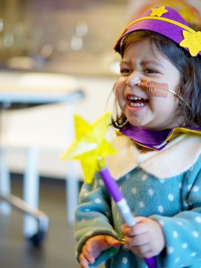 Child in a cape holding a magic wand with a star, indoor setting at Sofitel Brisbane Central