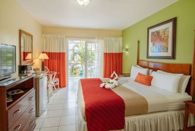 Cozy room featuring a king bed with colorful decor, a balcony view, and modern amenities in Deluxe Room at Bay Gardens Inn