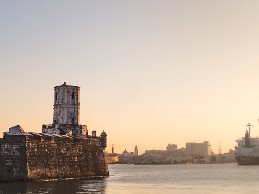 Fuerte histórico de piedra con torre de vigilancia junto al agua al atardecer cerca de Camino Real Hotels
