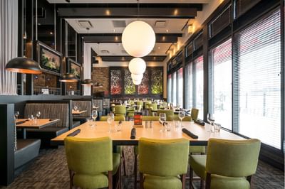 Dining tables set up with comfy chairs in Pacini Restaurant at Acclaim Hotel Calgary