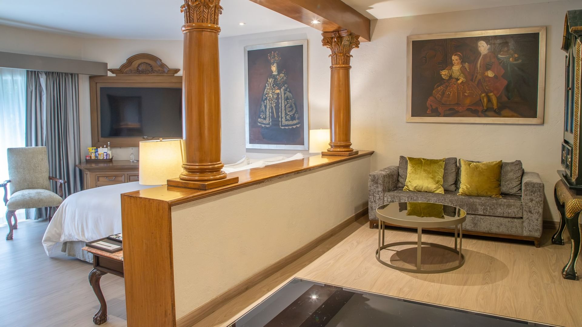 Spacious King Governor Suite with ornate columns, seating area, and colonial artwork at Quinta Real Guadalajara
