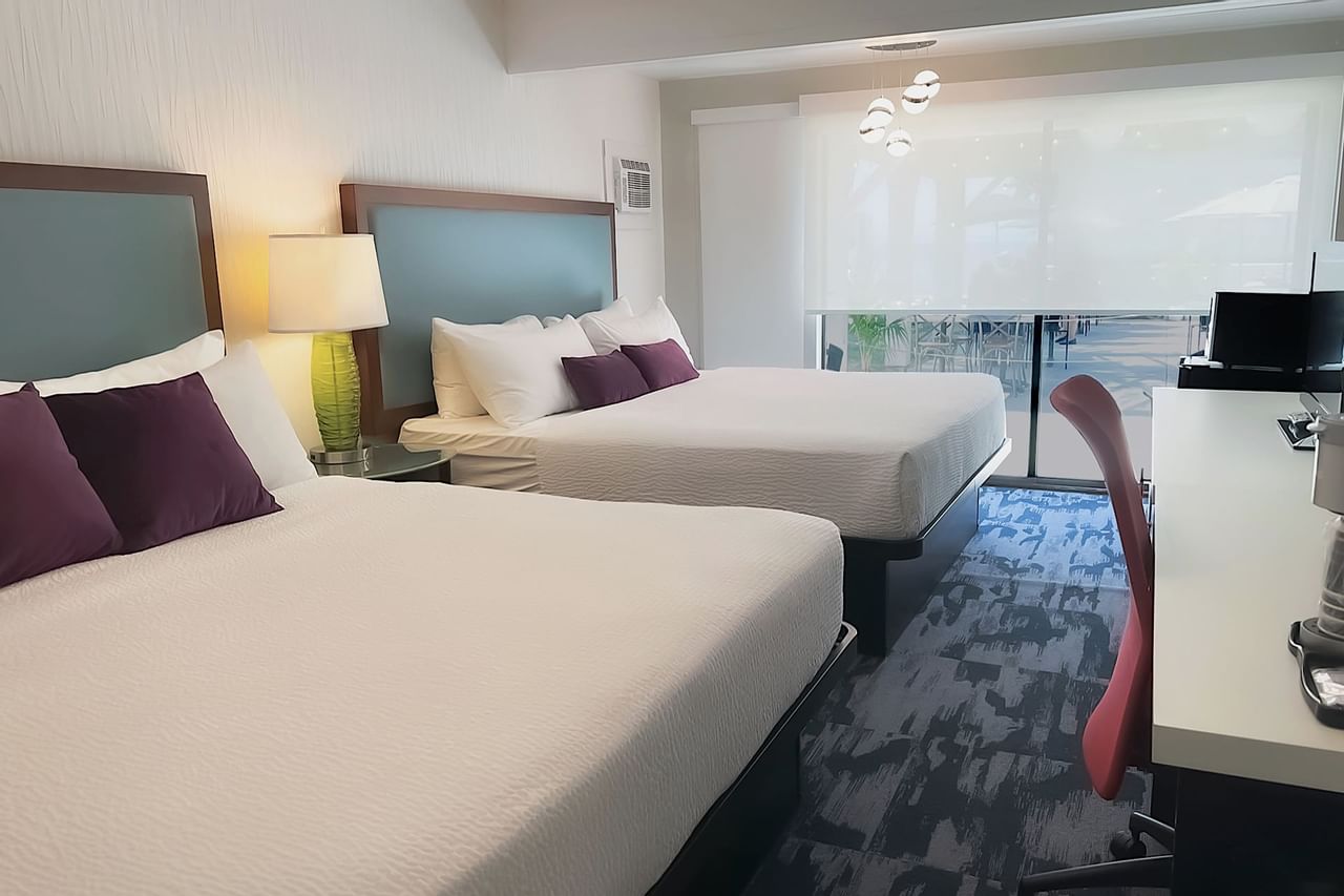 Guest room with two king beds, large desk, tv, patio doors, chair