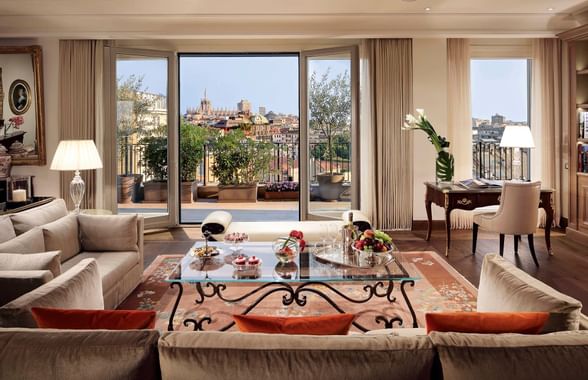 Living area with comfy sofas, coffee table, lamps & balcony view in a suite at Palazzo Parigi