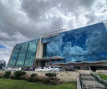 Exterior of Hotel B3 Sibelius with a blue glass facade & parked cars under cloudy skies, an elite hotel in Bogota, Colombia