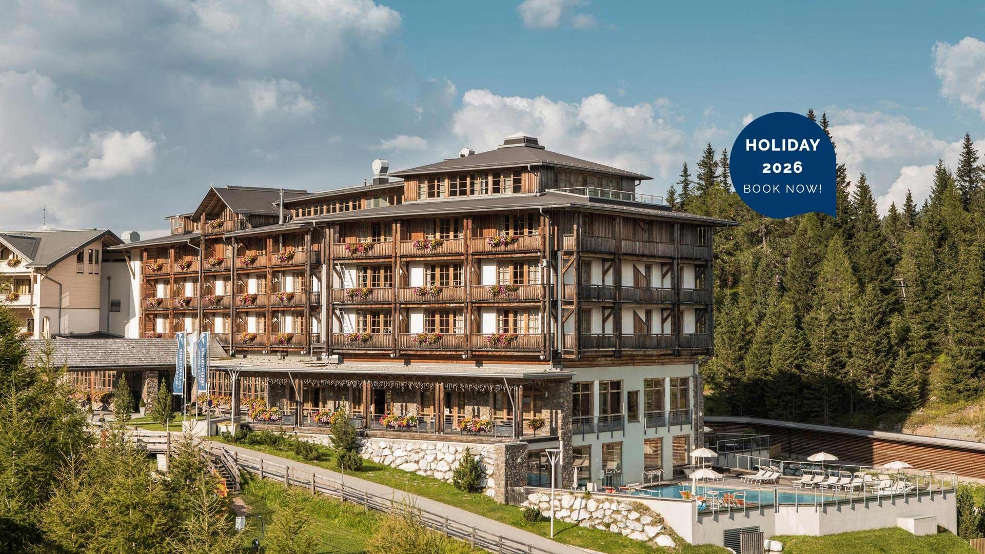 Luftaufnahme eines großen, hölzernen Hotels mit Pool und umgebenden Wäldern.