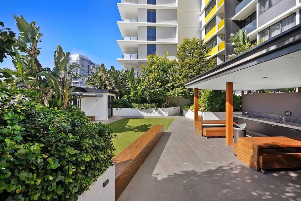 Outdoor BBQ area with arranged wooden seats and vanity with tiled floors by the greeny garden at Alcyone Hotel Residences