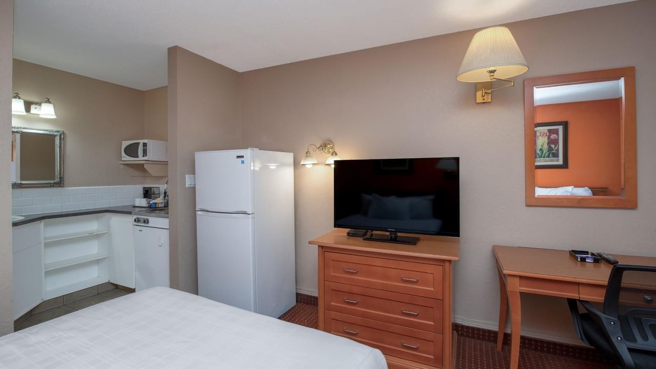 Guest room at Coast Red Deer Hotel with kitchenette, full-size fridge, TV and desk
