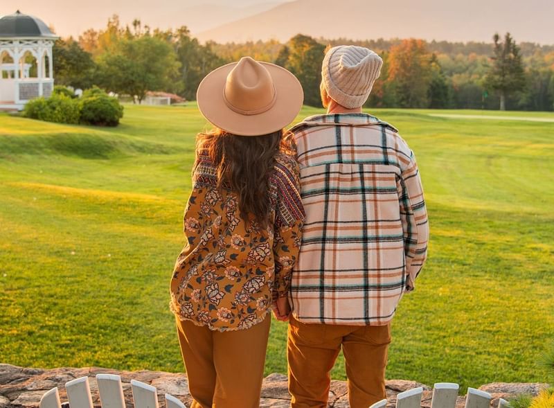 Couple in cozy autumn attire looking out over a golf course towards the mountains near Mountain View Grand Resort & Spa