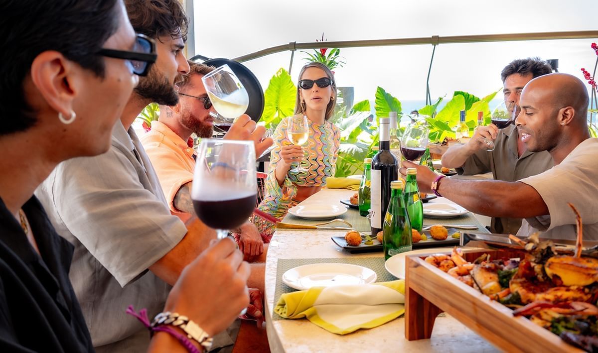 People dining outdoors with wine and a seafood meal at Almar Beach Resort