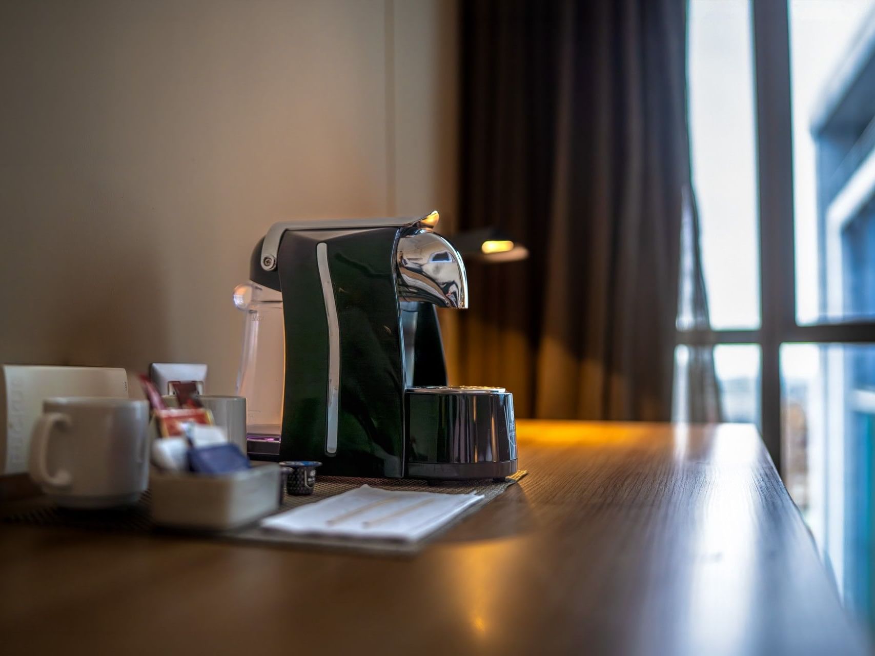 Cafetera con tazas y servilletas sobre una mesa en un hotel.