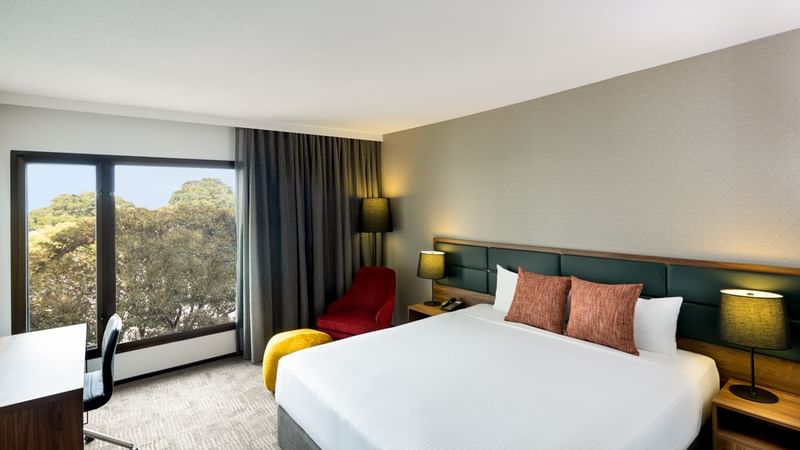 Work desk facing bed with seating by the window in Deluxe Room at Novotel Sydney International Airport