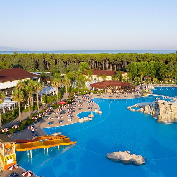 Aerial view of outdoor pool area with sun beds surrounded by lush greenery at Falkensteiner Club Funimation Garden Calabria