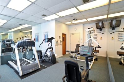 Exercise treadmill beside elliptical machine near weight equipment and bike in Gym at Avon Old Farms Hotel